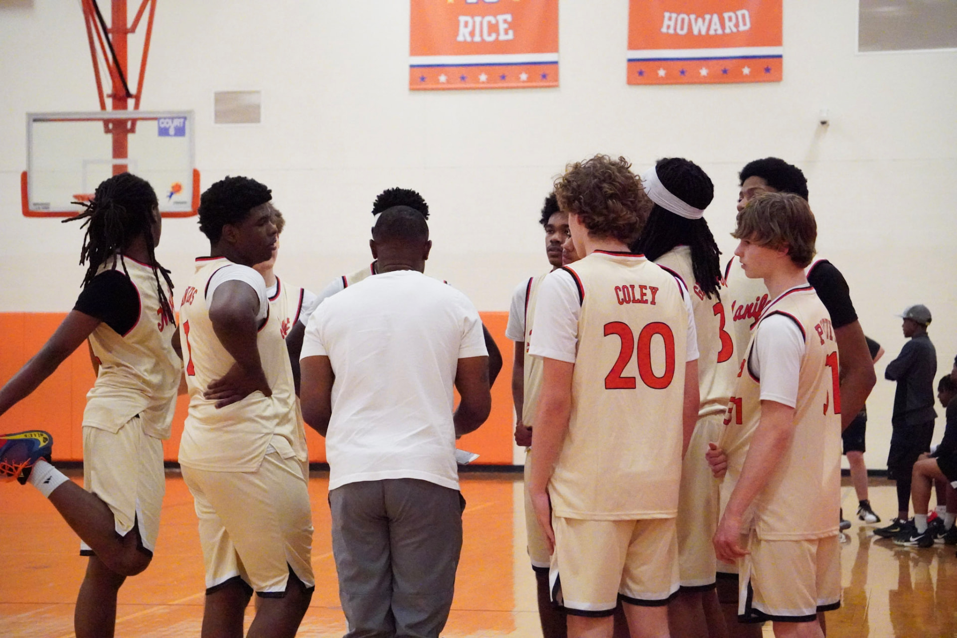 Coach speaking to a team of players huddled together on the court during a timeout.
