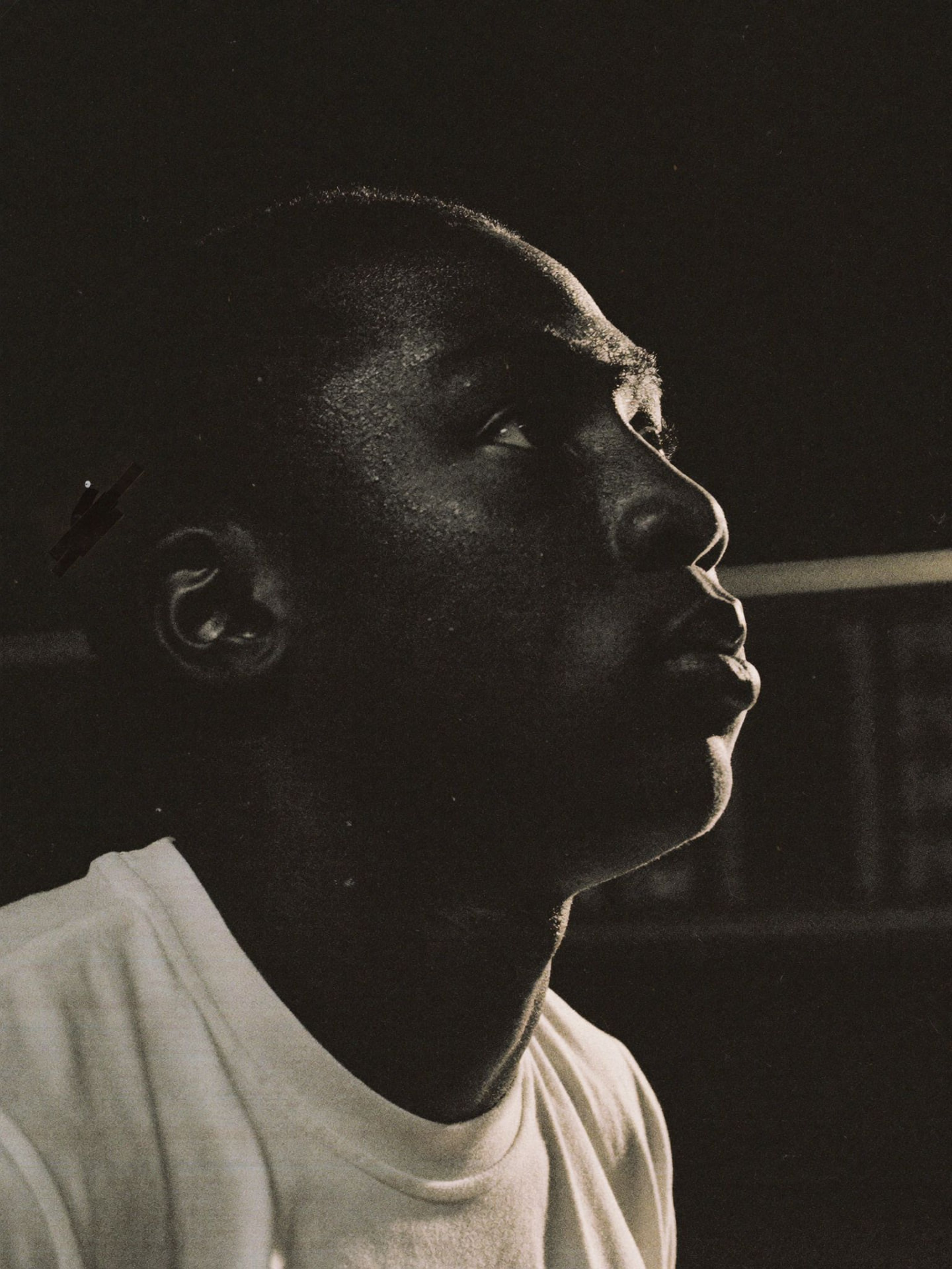 Coach Antonio Hicks watching play from the bench, high-contrast black and white.